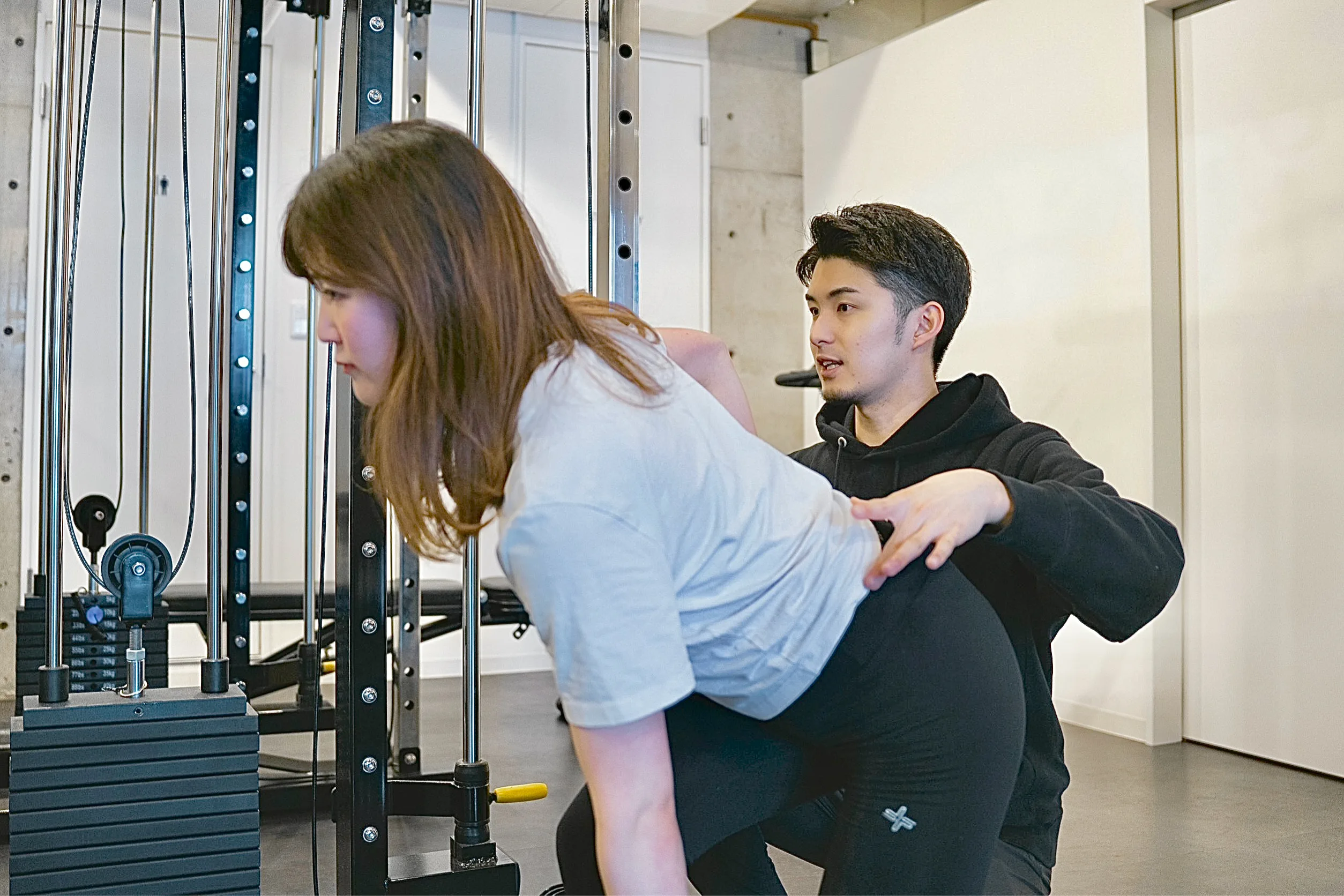 表参道・外苑前のパーソナルジム
QUALITAS青山外苑前店で男性トレーナーにトレーニング指導を受けている女性