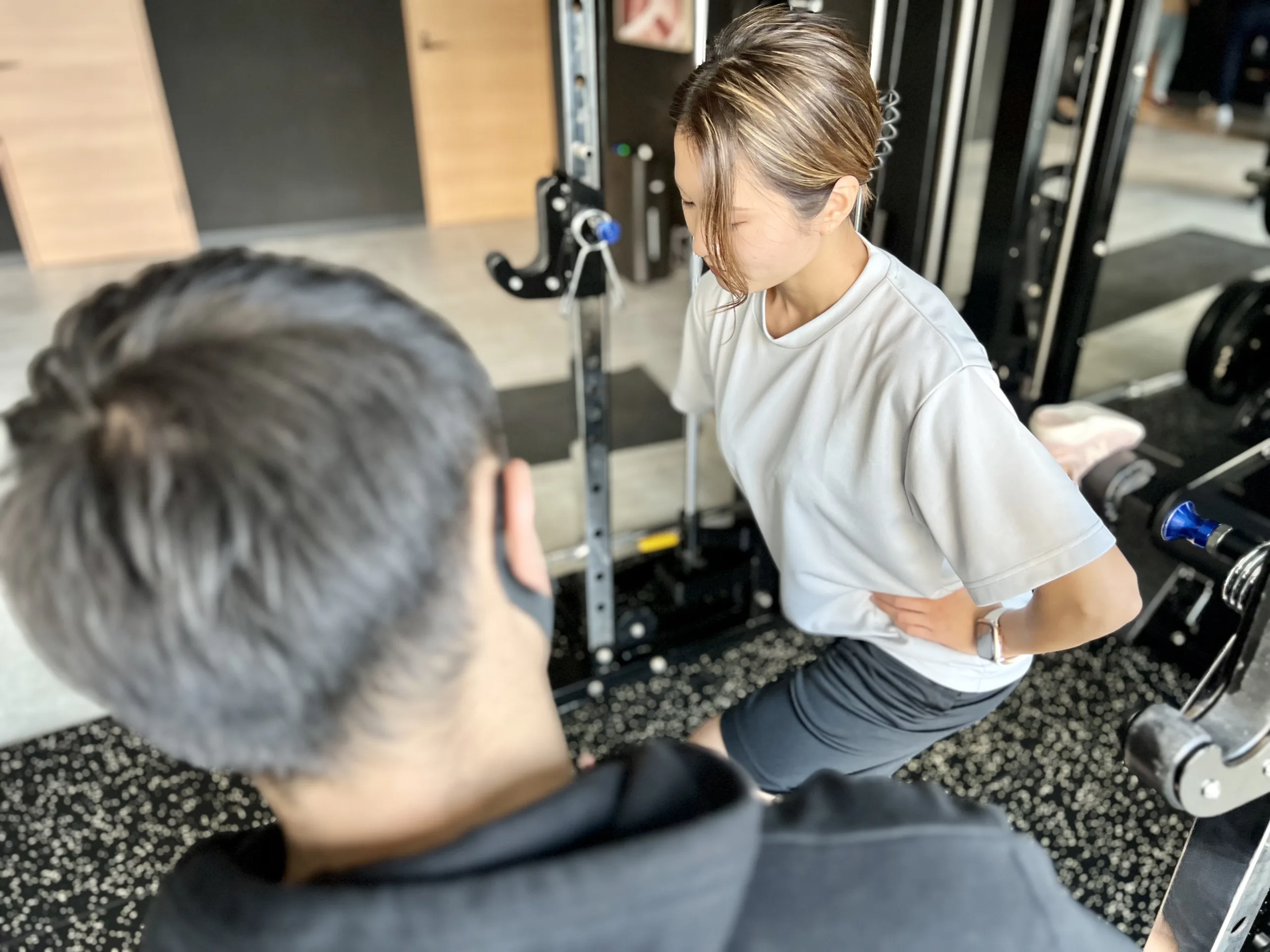 表参道・外苑前のパーソナルジムQUALITAS青山外苑前店で男性トレーナーにトレーニング指導を受けている女性