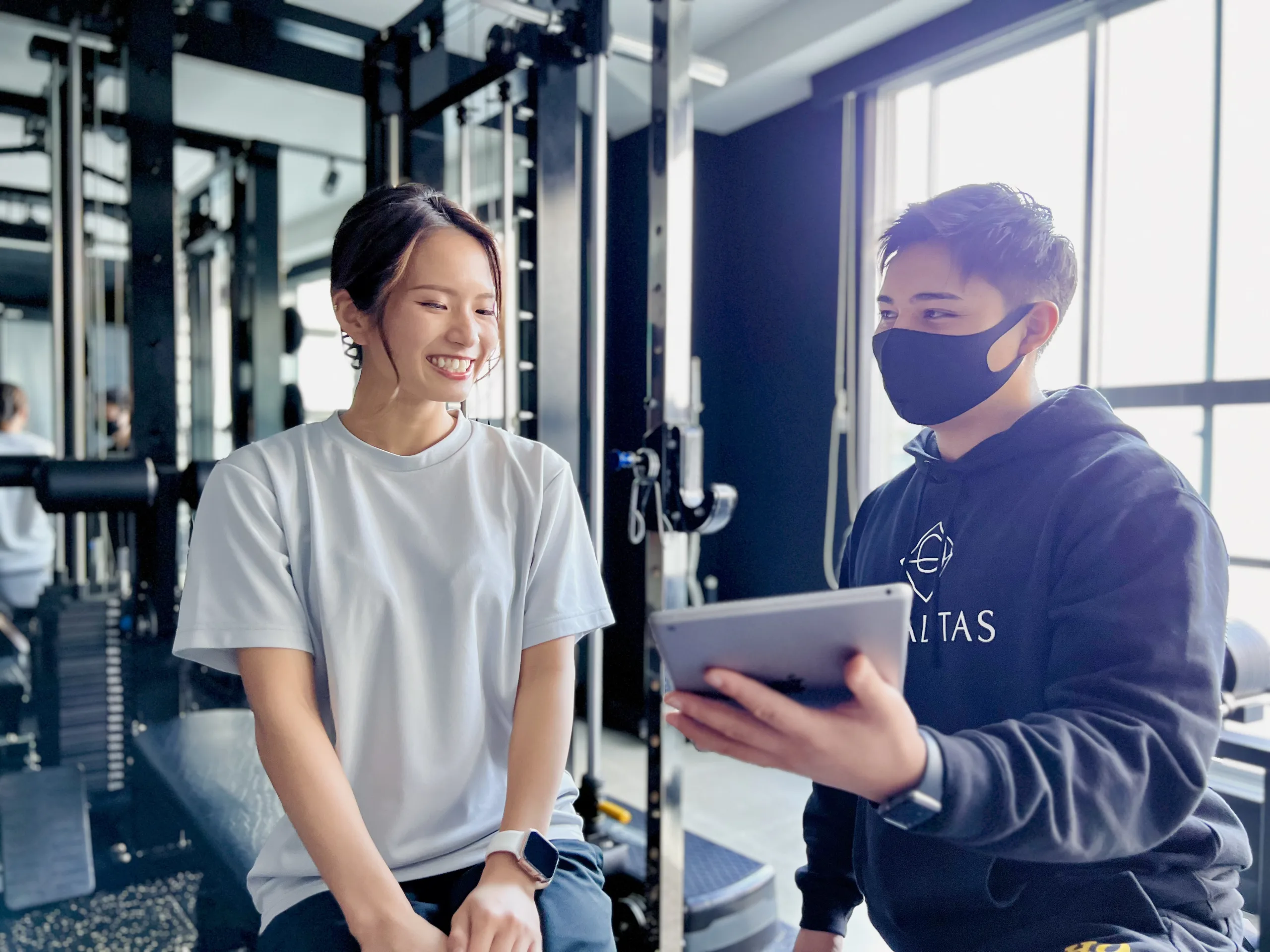 表参道・外苑前のパーソナルジムQUALITAS青山外苑前店で男性トレーナーにカウンセリングを受けている女性