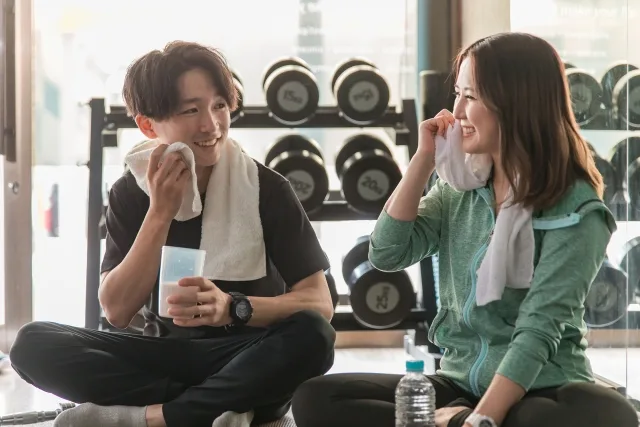 スポーツジムに通う休憩をする男女