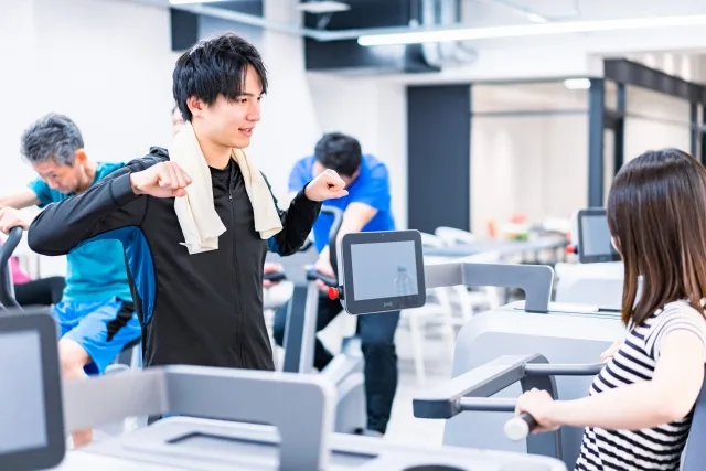 ジムでトレーナーの指導を受ける若い女性