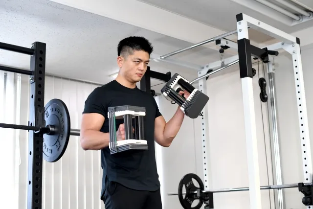 ジムでダンベルを持ってトレーニングをしている男性